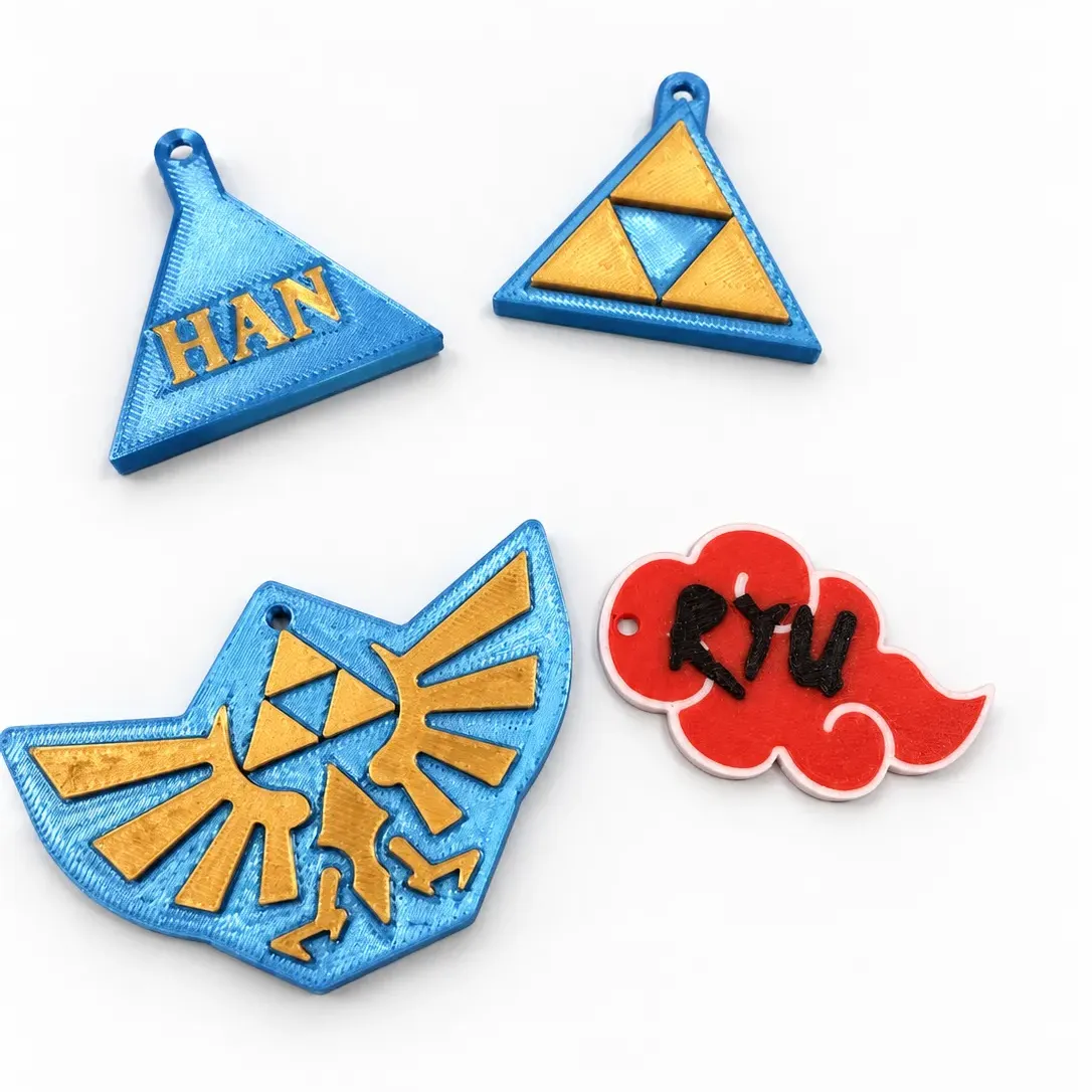 Etiquetas para mochila con formas de Zelda y Naruto: trifuerza, escudo de Hyrule y nube Akatsuki, con los nombres Han y Ryu